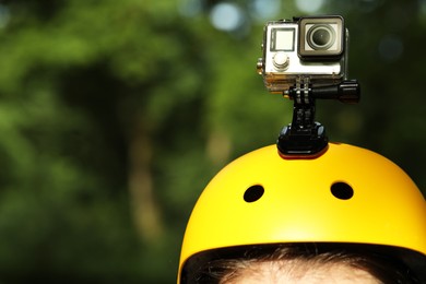 Man with modern action camera on helmet outdoors, closeup. Space for text