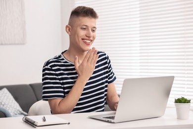 Young man using sign language during video call indoors