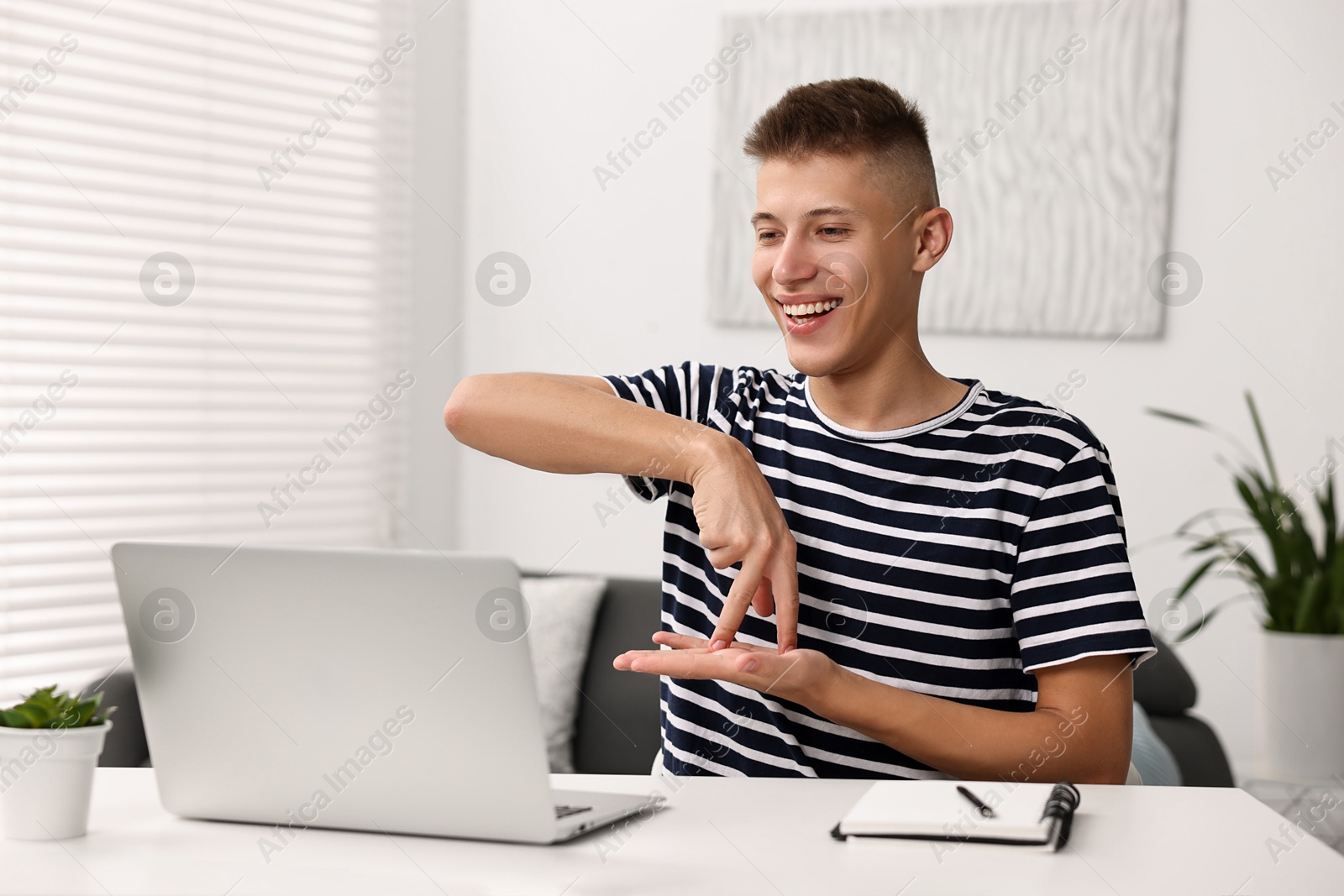 Photo of Young man using sign language during video call indoors