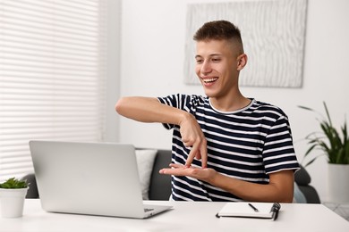 Young man using sign language during video call indoors