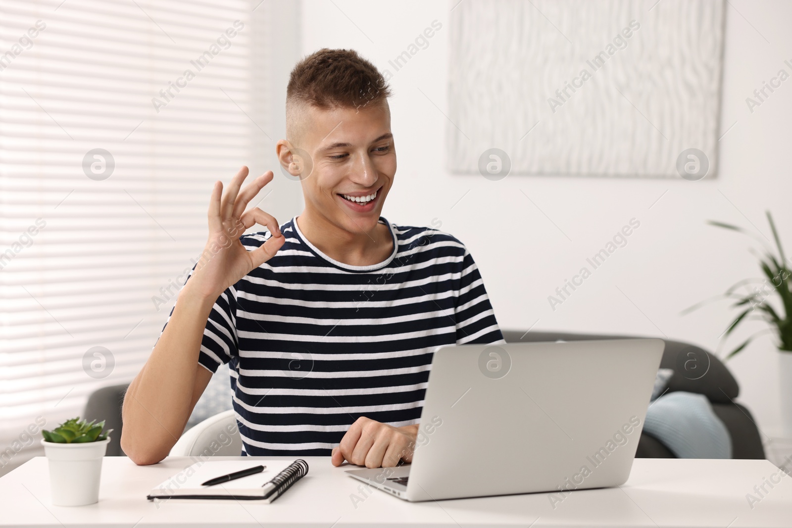 Photo of Young man using sign language during video call indoors