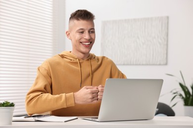 Photo of Young man using sign language during video call indoors