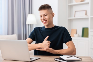 Young man using sign language during video call indoors