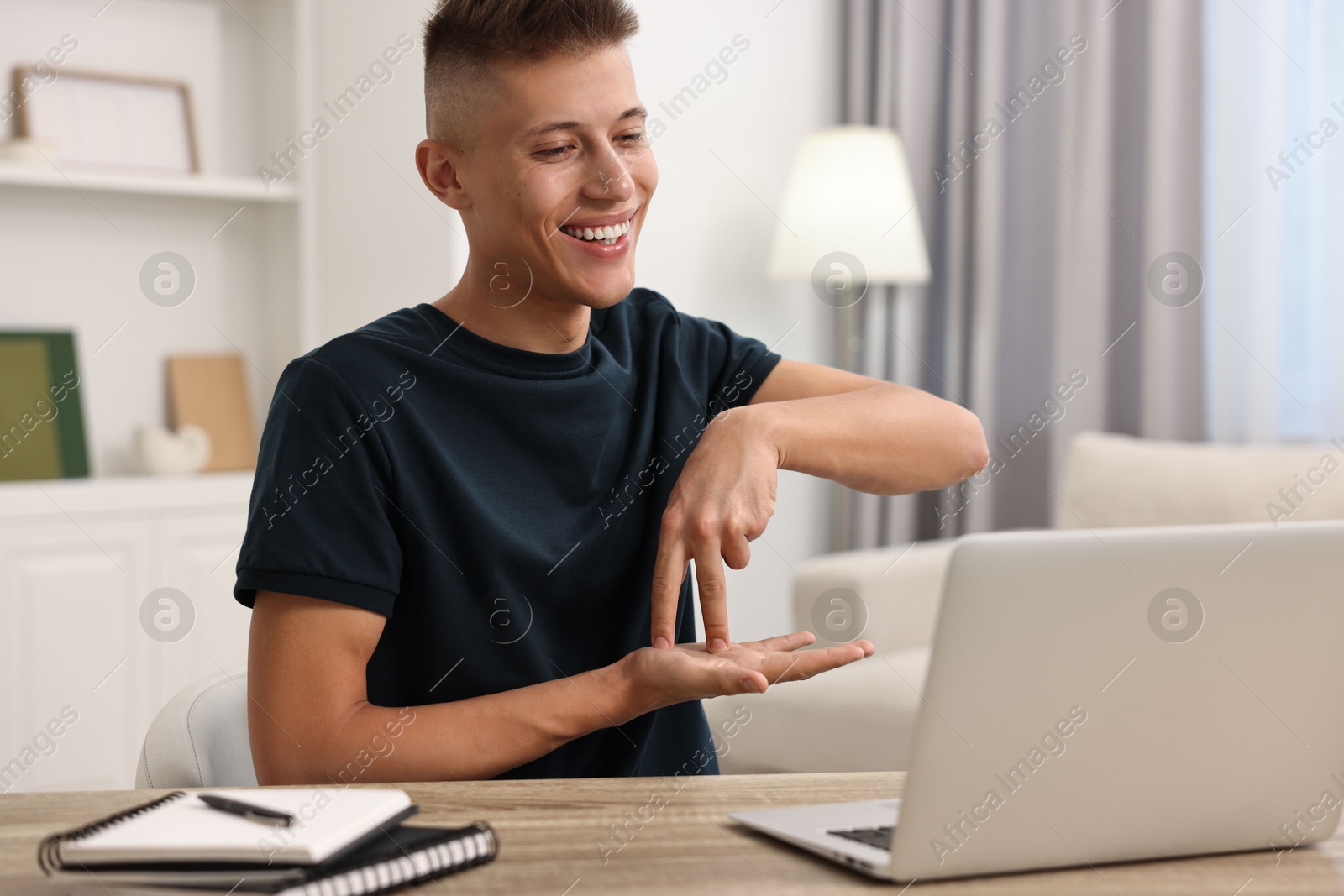 Photo of Young man using sign language during video call indoors