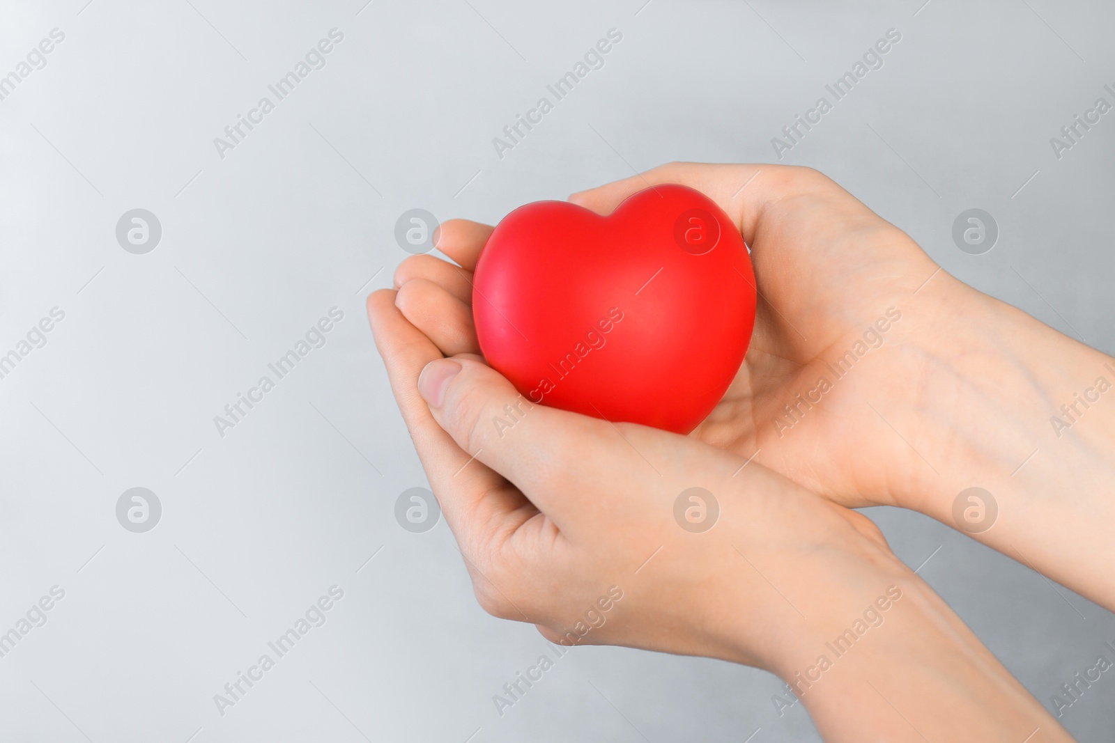 Photo of Woman holding red heart on grey background, closeup. Space for text