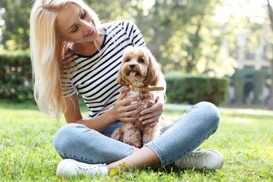 Photo of Beautiful young woman with cute dog on green grass in park