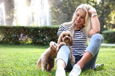 Photo of Beautiful young woman with cute dog on green grass in park