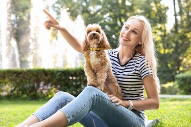 Beautiful young woman with cute dog on green grass in park