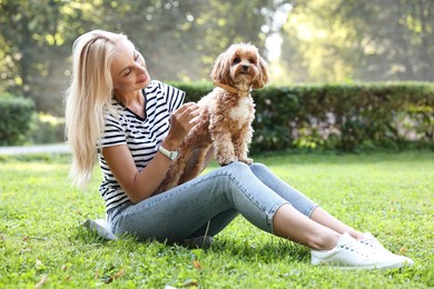 Beautiful young woman with cute dog on green grass in park