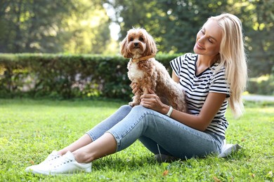 Beautiful young woman with cute dog on green grass in park