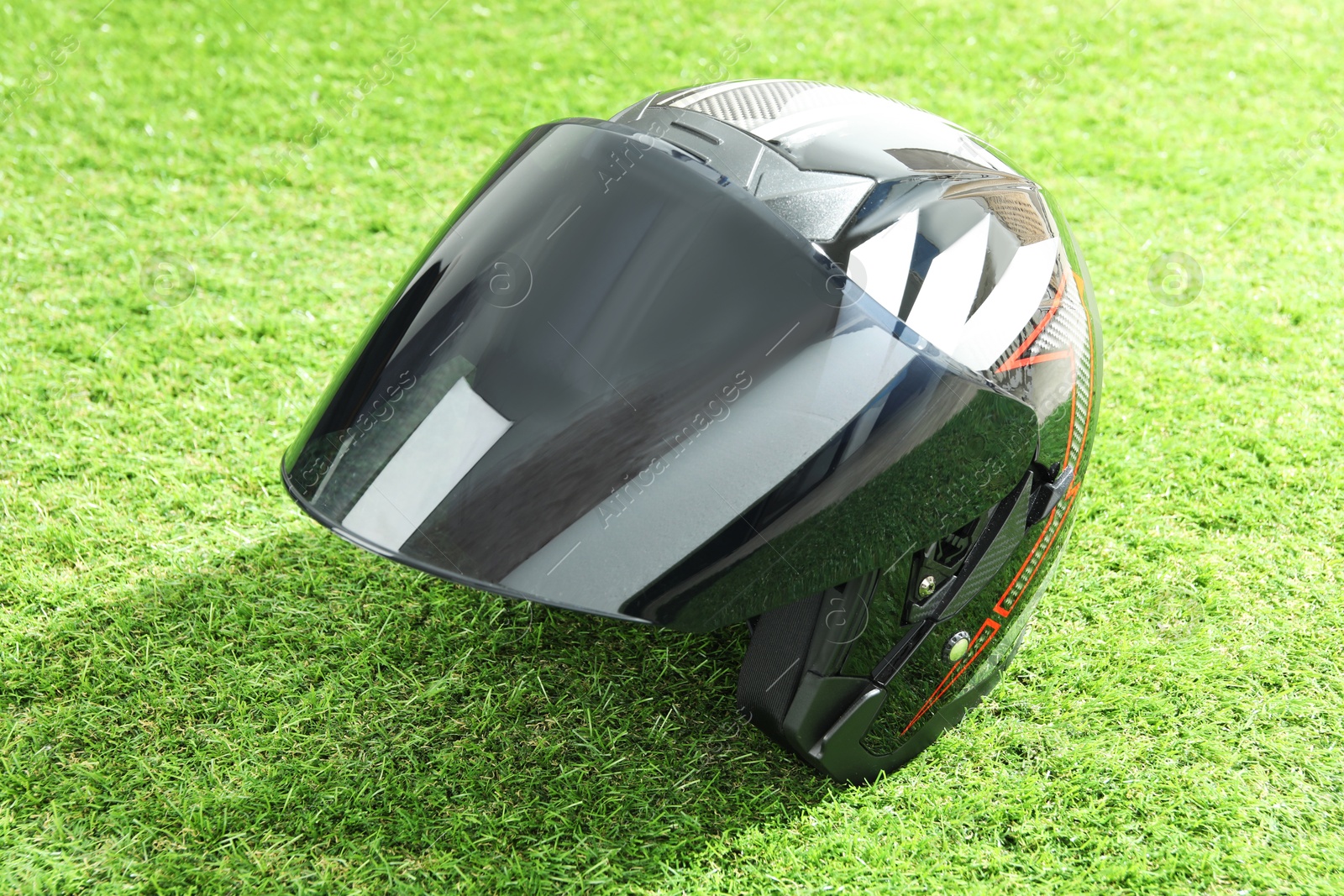 Photo of Modern motorcycle helmet with visor on green grass outdoors