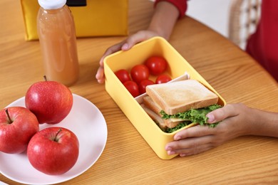 Photo of Girl with lunch box of healthy food at wooden table in kitchen, closeup