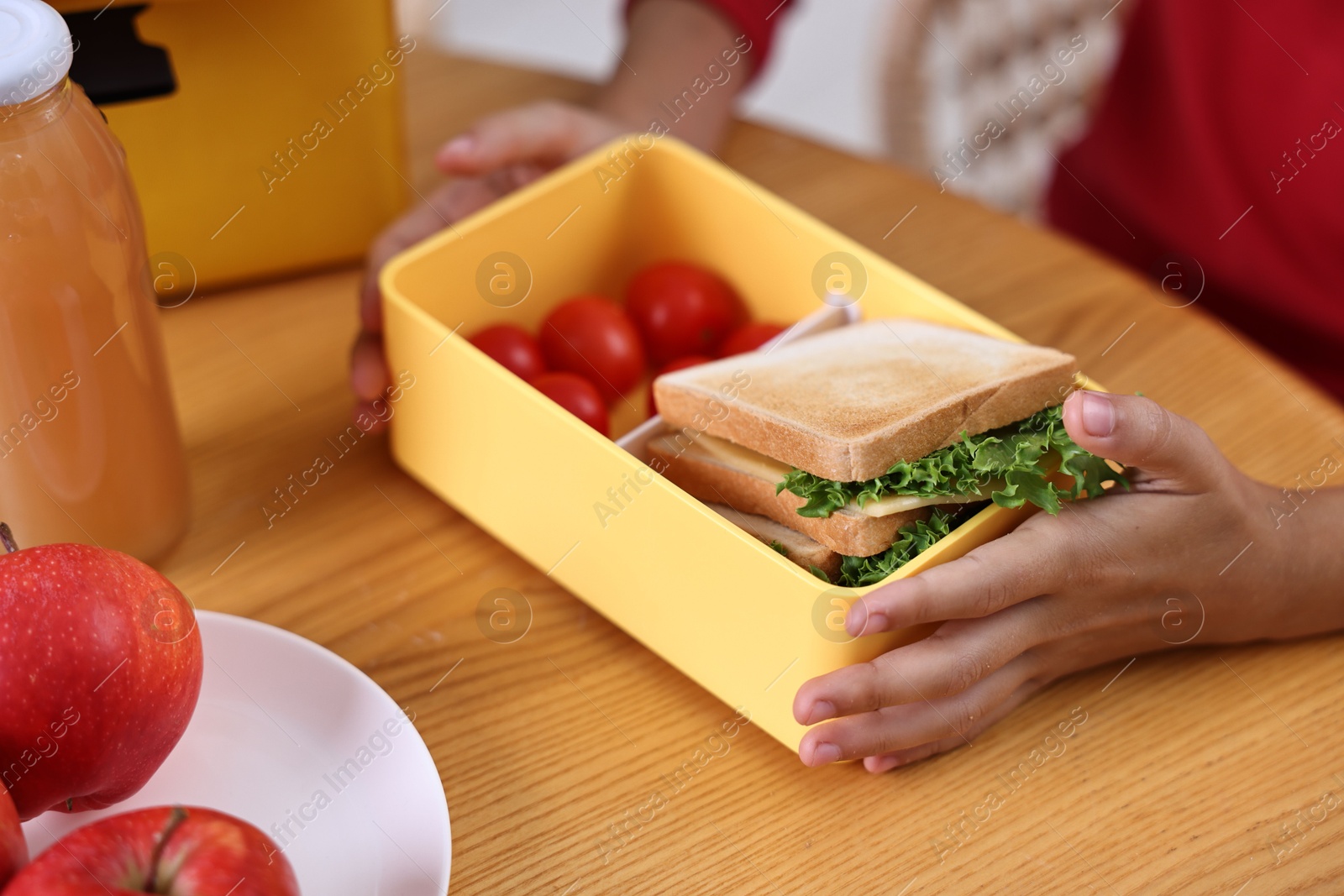 Photo of Girl with lunch box of healthy food at wooden table in kitchen, closeup