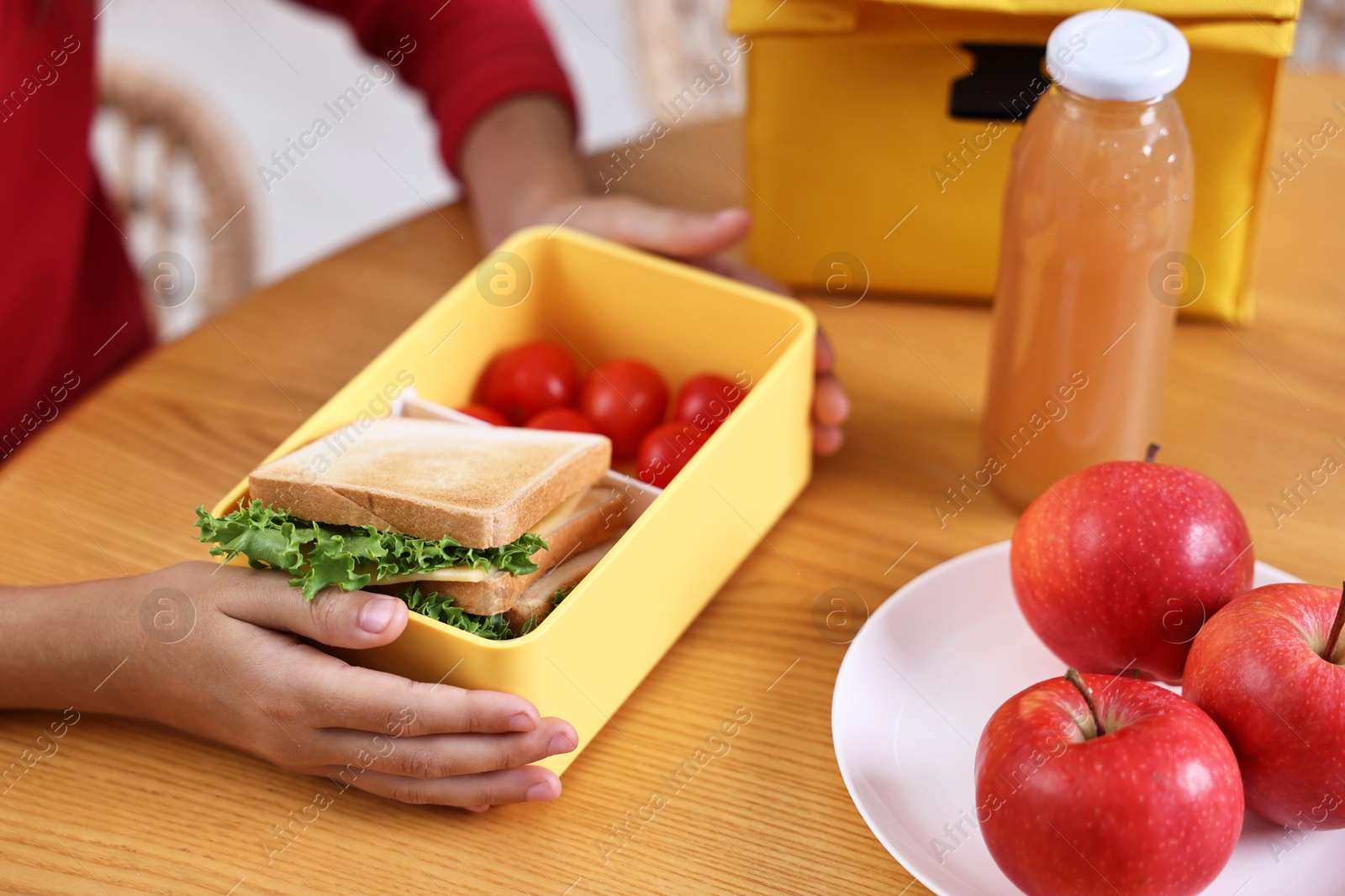 Photo of Girl with lunch box of healthy food at wooden table in kitchen, closeup