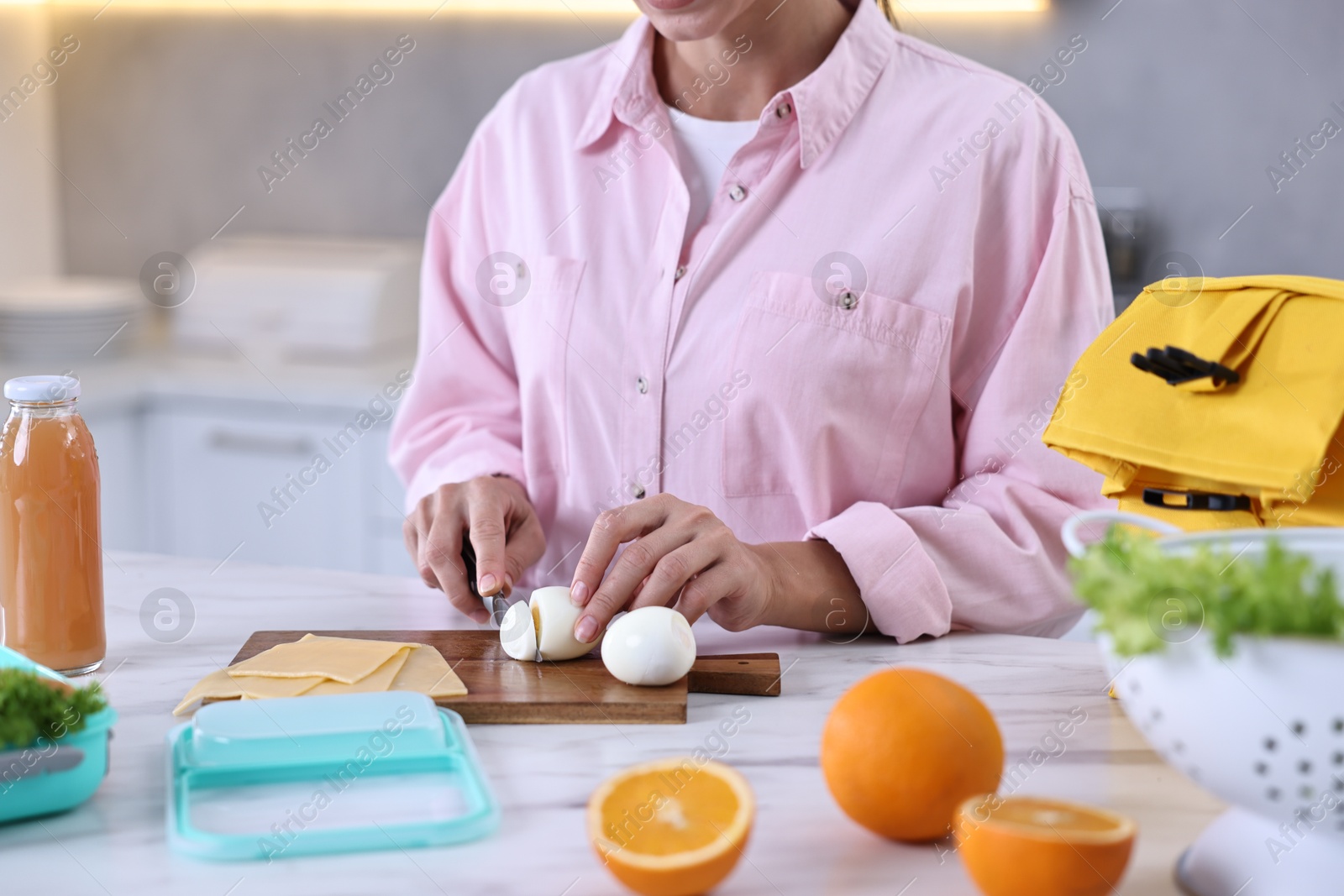 Photo of Woman making snacks for school lunch box at white marble table in kitchen, closeup