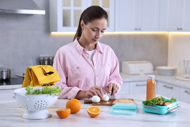 Photo of Woman making snacks for school lunch box at white marble table in kitchen