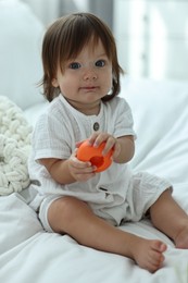 Cute little baby with toys on bed at home