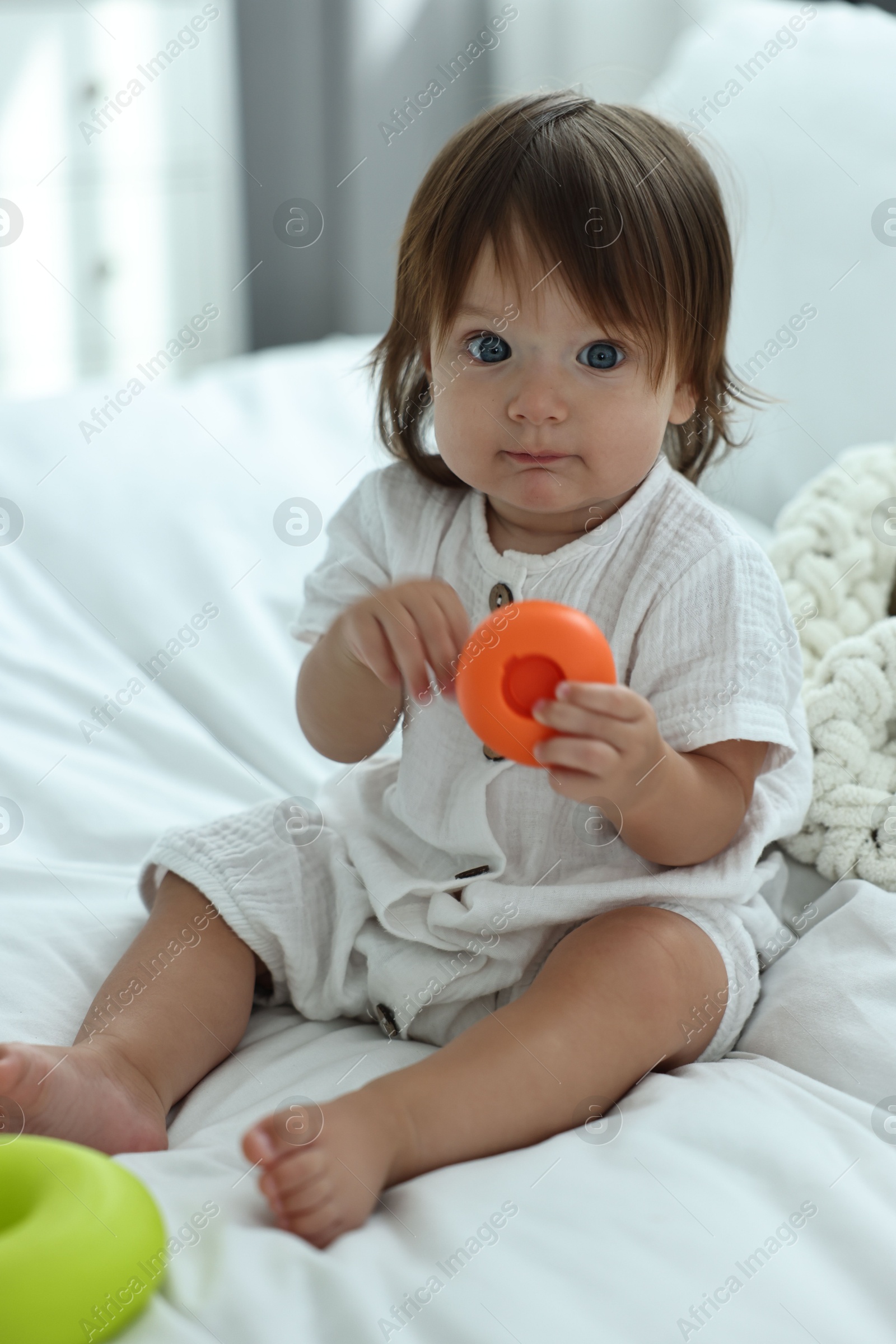 Photo of Cute little baby with toys on bed at home