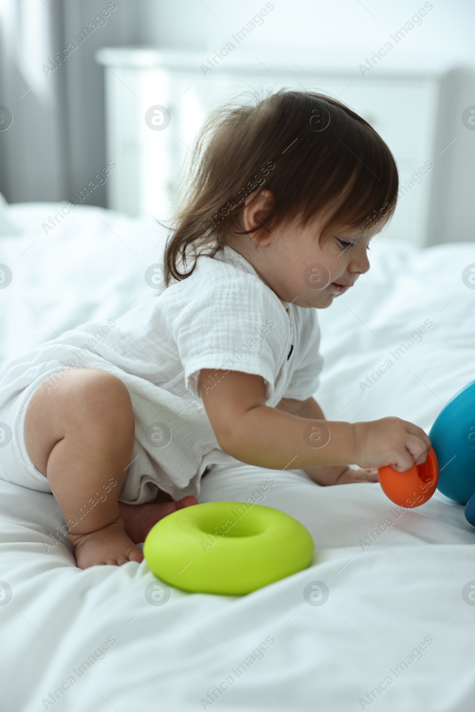 Photo of Cute little baby with toys on bed at home