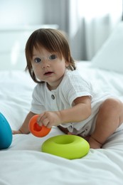 Photo of Cute little baby with toys on bed at home