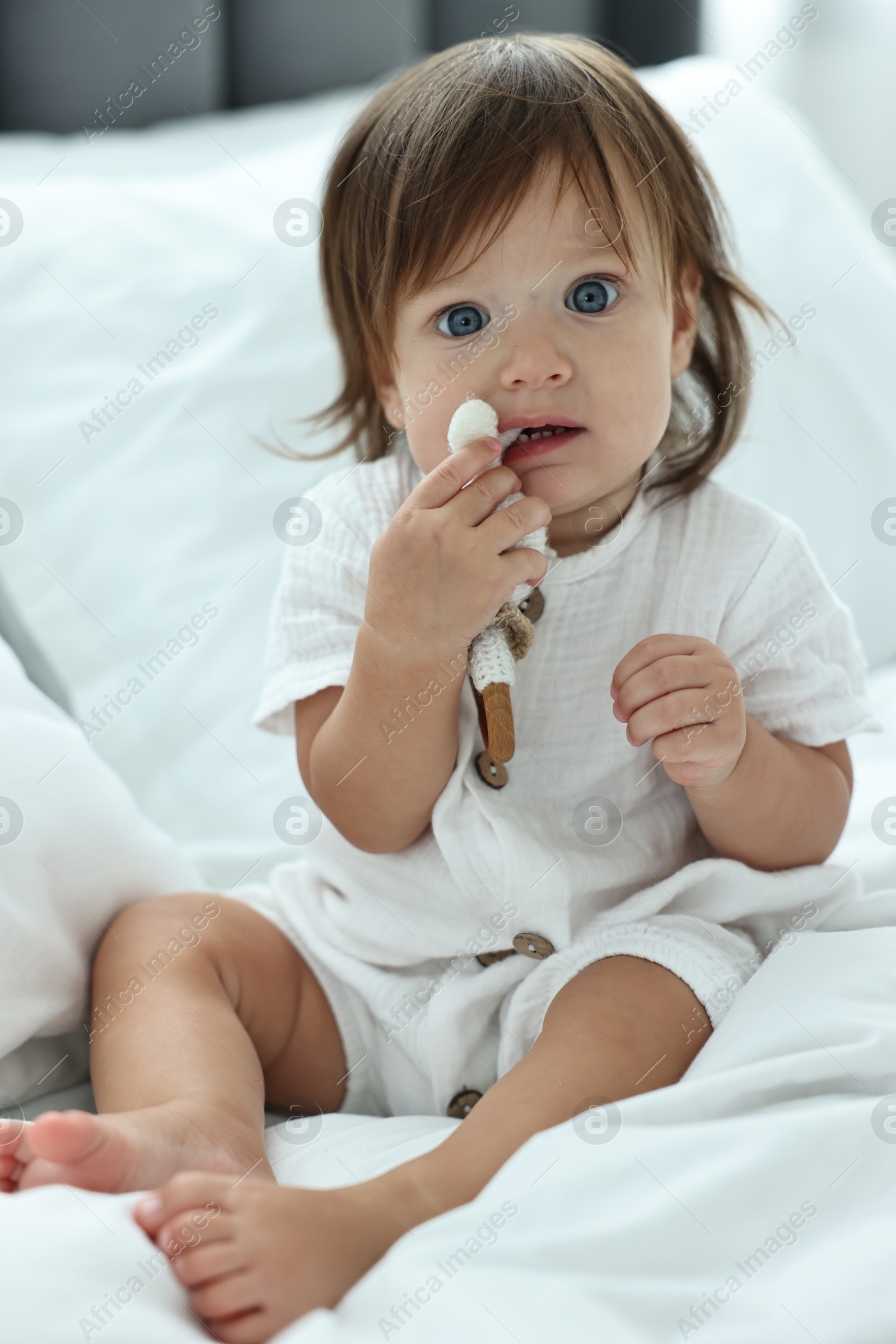 Photo of Cute little baby with rattle on bed at home