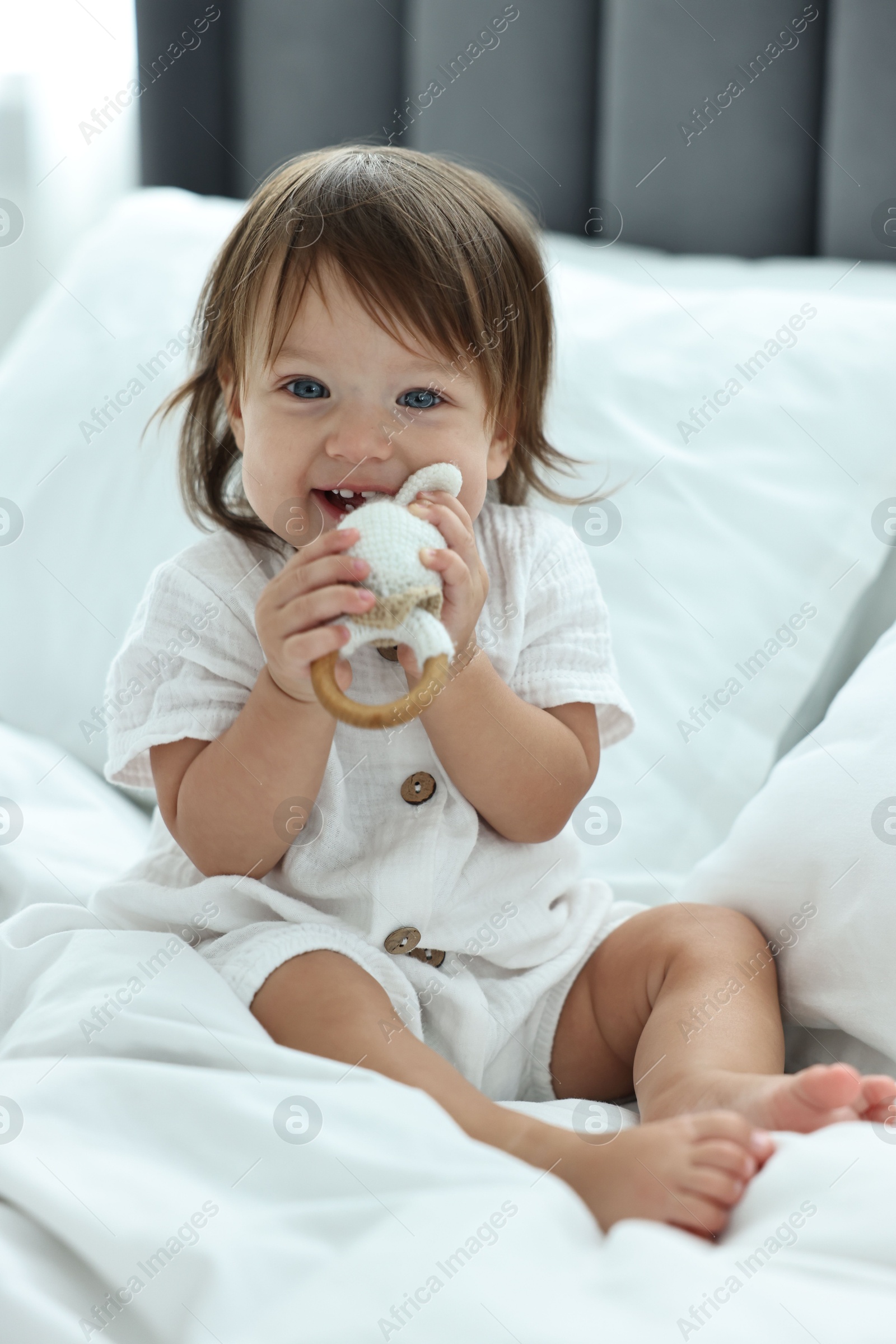 Photo of Cute little baby with rattle on bed at home