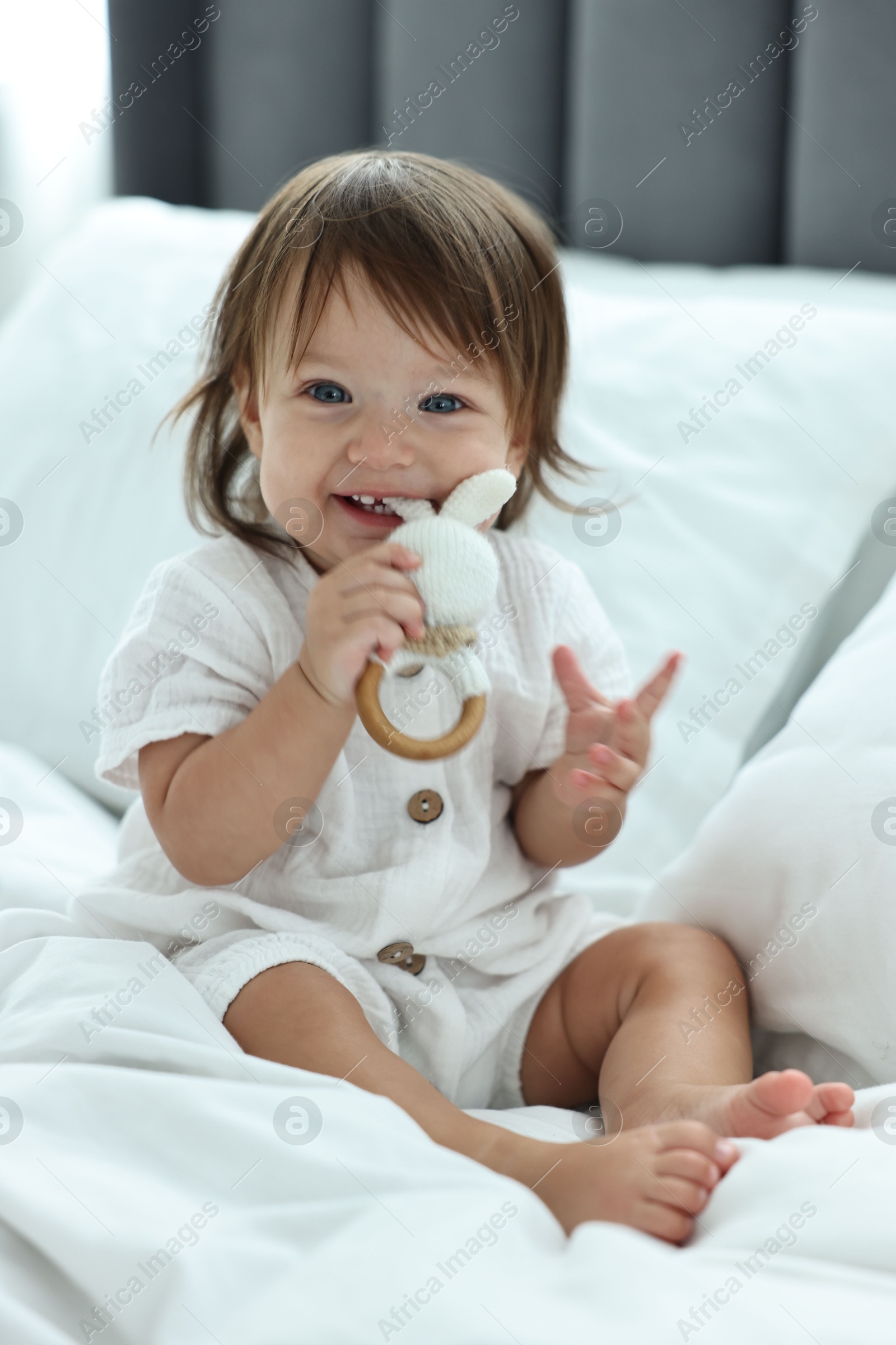 Photo of Cute little baby with rattle on bed at home