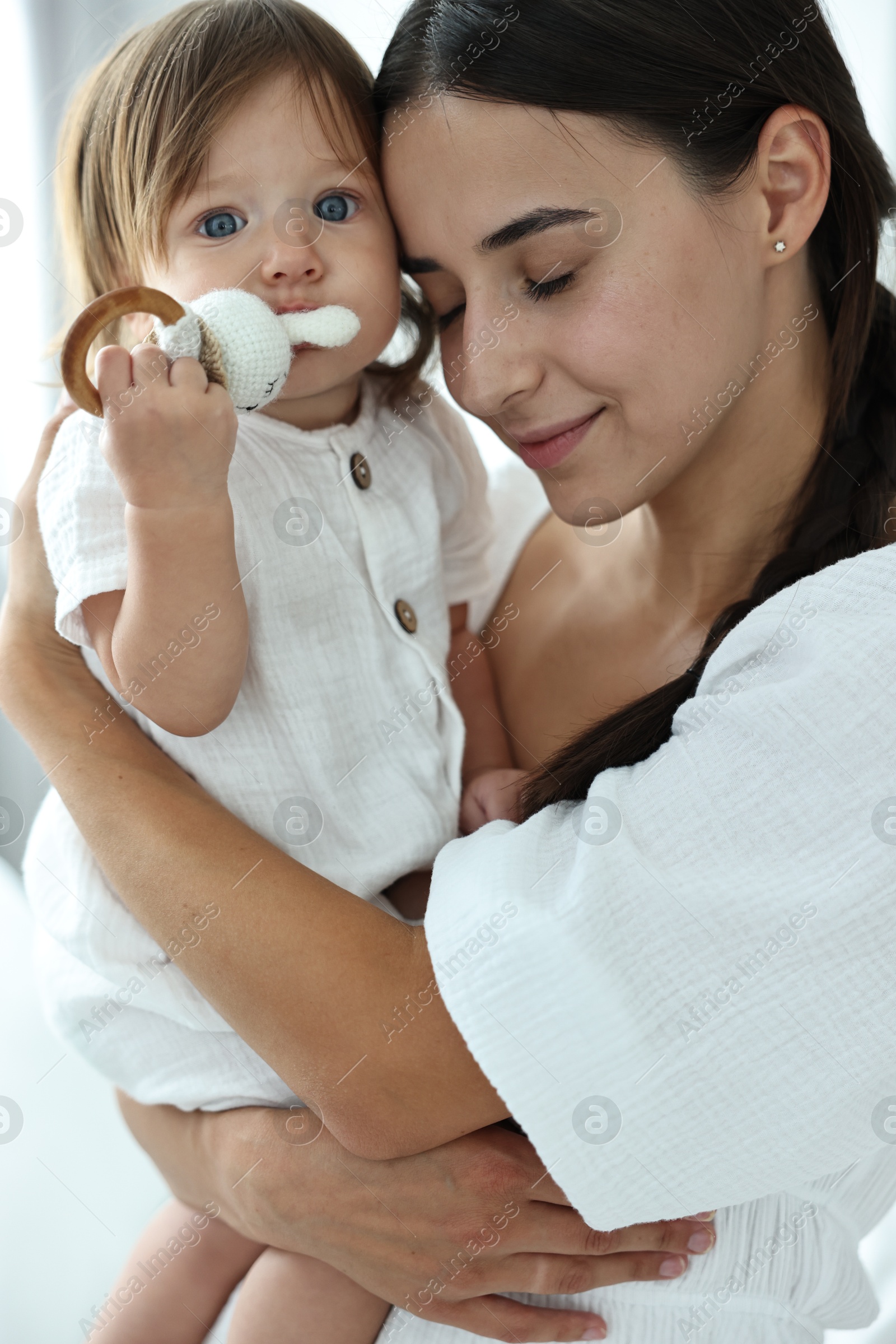 Photo of Beautiful young mother and her cute little baby with rattle indoors