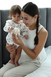 Beautiful young mother and her cute little baby with rabbit toy on bed at home