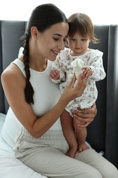 Photo of Beautiful young mother and her cute little baby with rabbit toy on bed at home