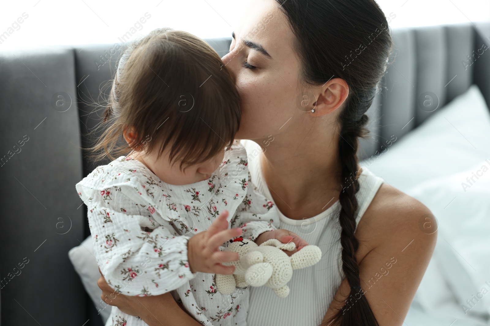 Photo of Beautiful young mother and her cute little baby with rabbit toy indoors