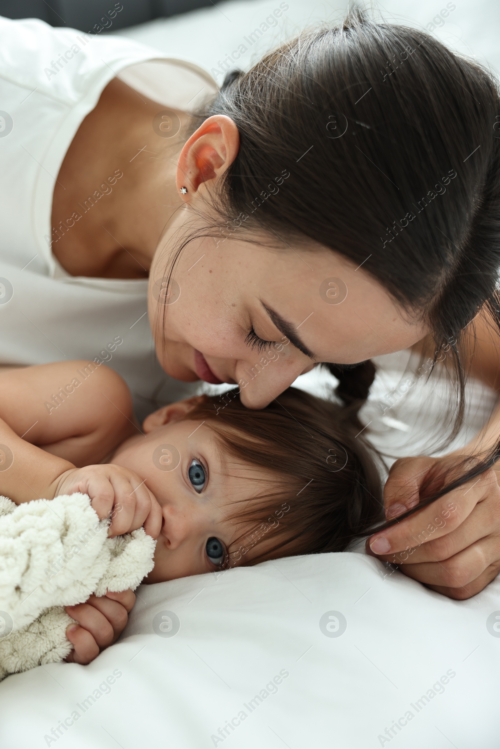 Photo of Beautiful young mother with her cute little baby on bed