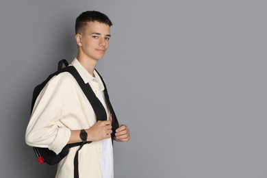 Photo of Portrait of teenage boy with backpack on grey background, space for text