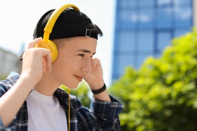 Photo of Portrait of teenage boy with headphones outdoors. Space for text