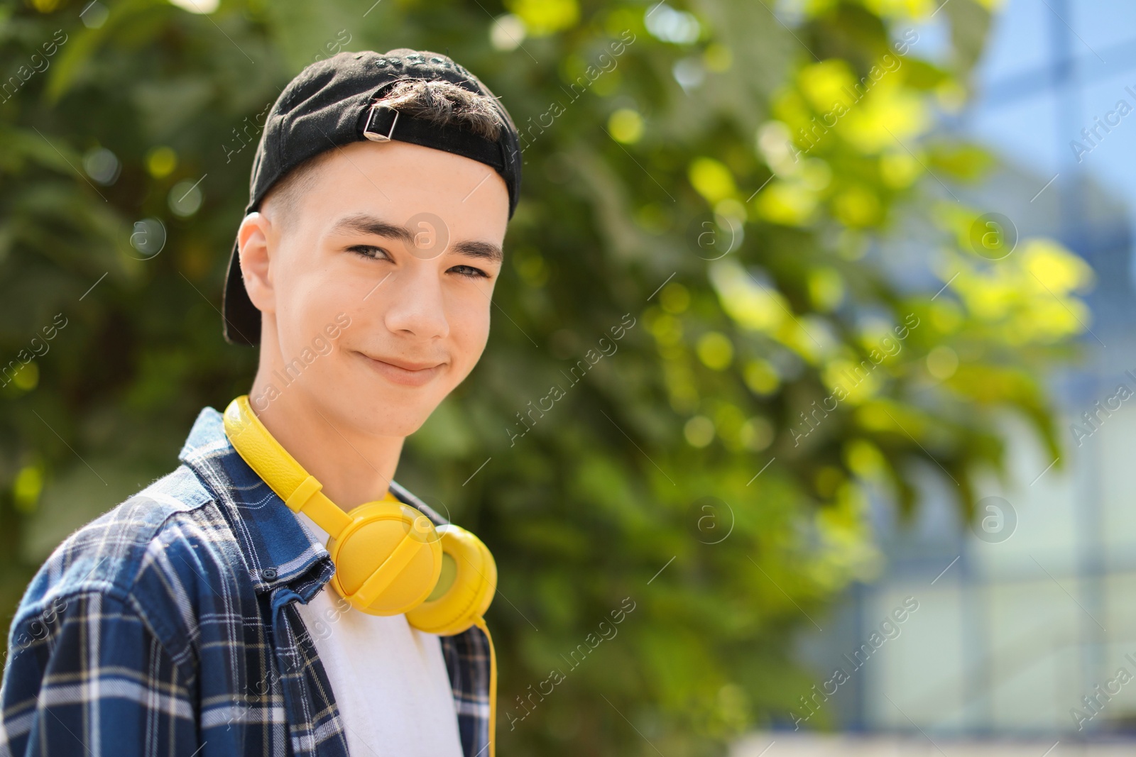 Photo of Portrait of teenage boy with headphones outdoors. Space for text