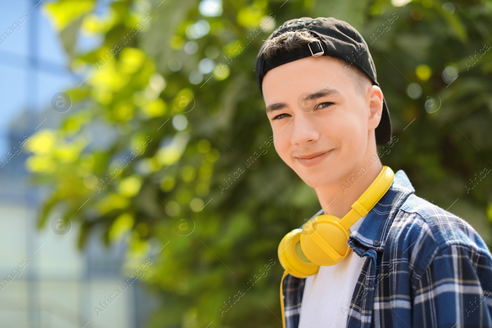 Photo of Portrait of teenage boy with headphones outdoors. Space for text