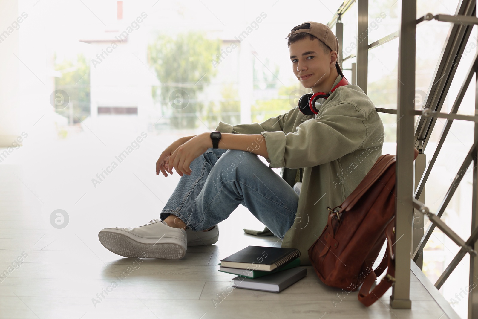 Photo of Full length portrait of teenage boy sitting on floor near railings. Space for text