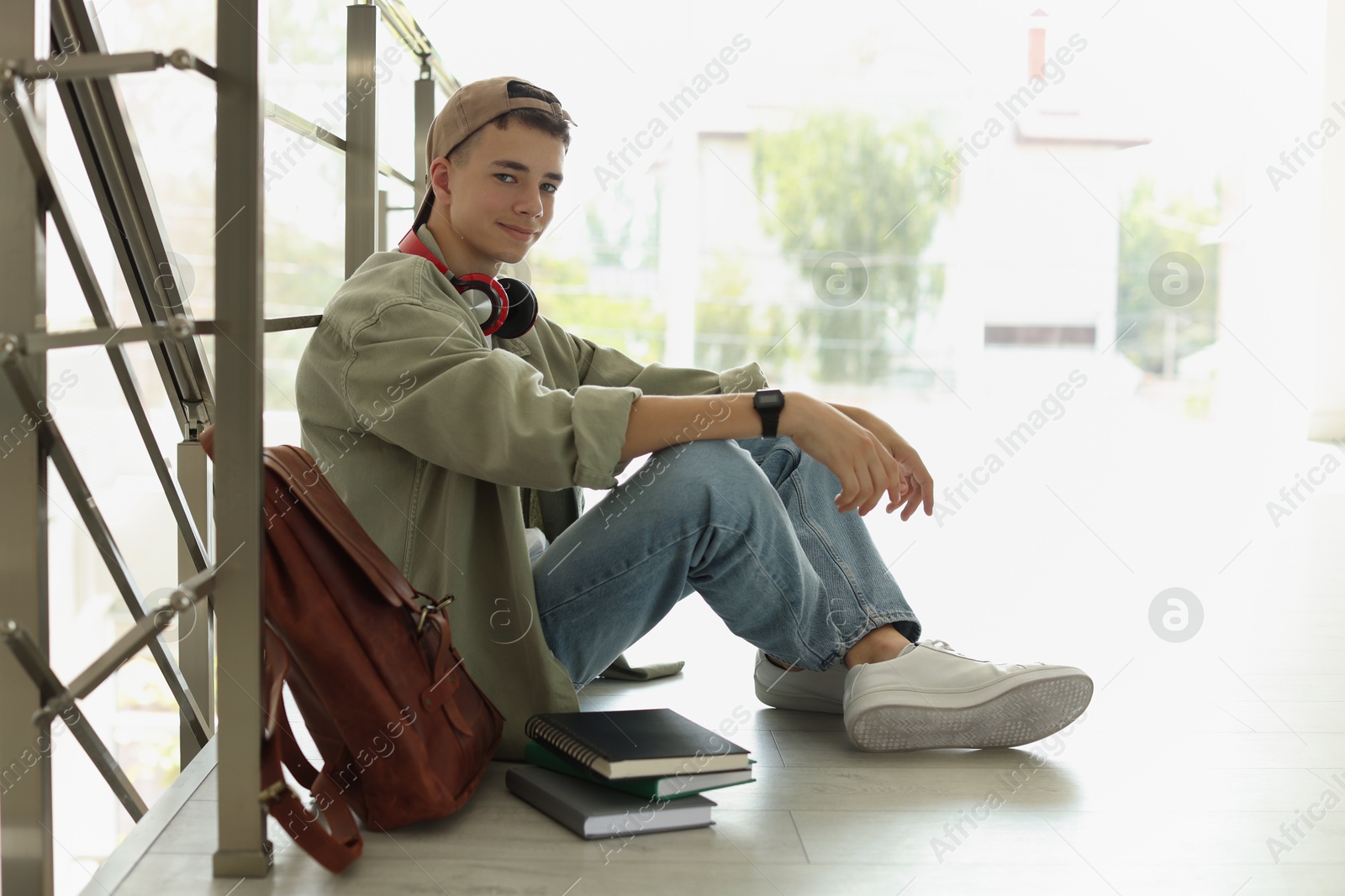 Photo of Full length portrait of teenage boy sitting on floor near railings