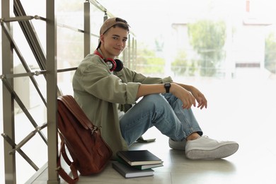 Full length portrait of teenage boy sitting on floor near railings