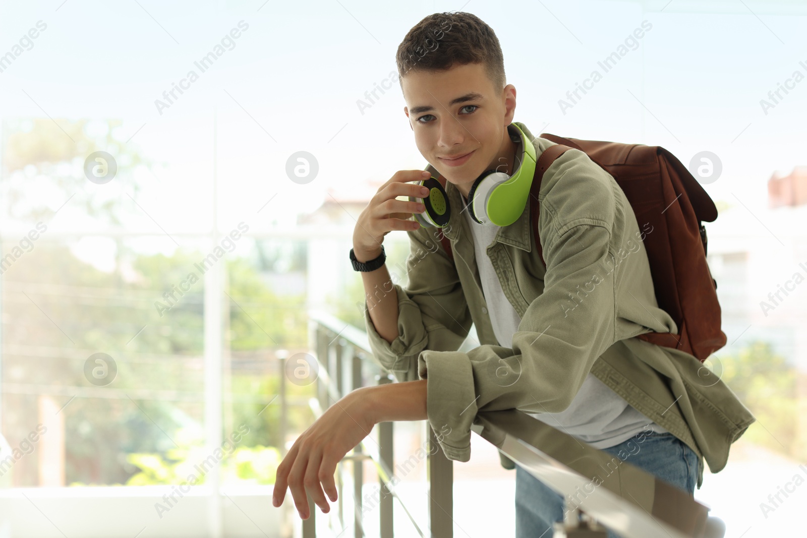 Photo of Portrait of teenage boy near railings indoors. Space for text