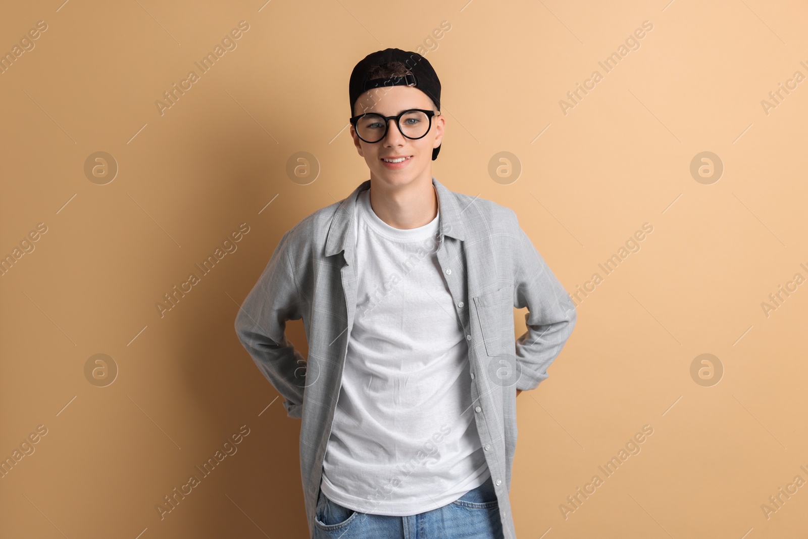 Photo of Portrait of smiling teenage boy on dark beige background