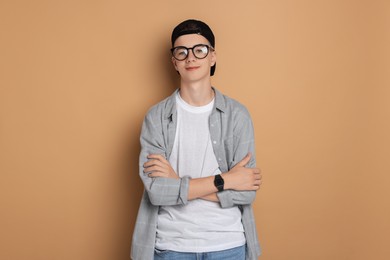 Portrait of teenage boy with crossed arms on dark beige background