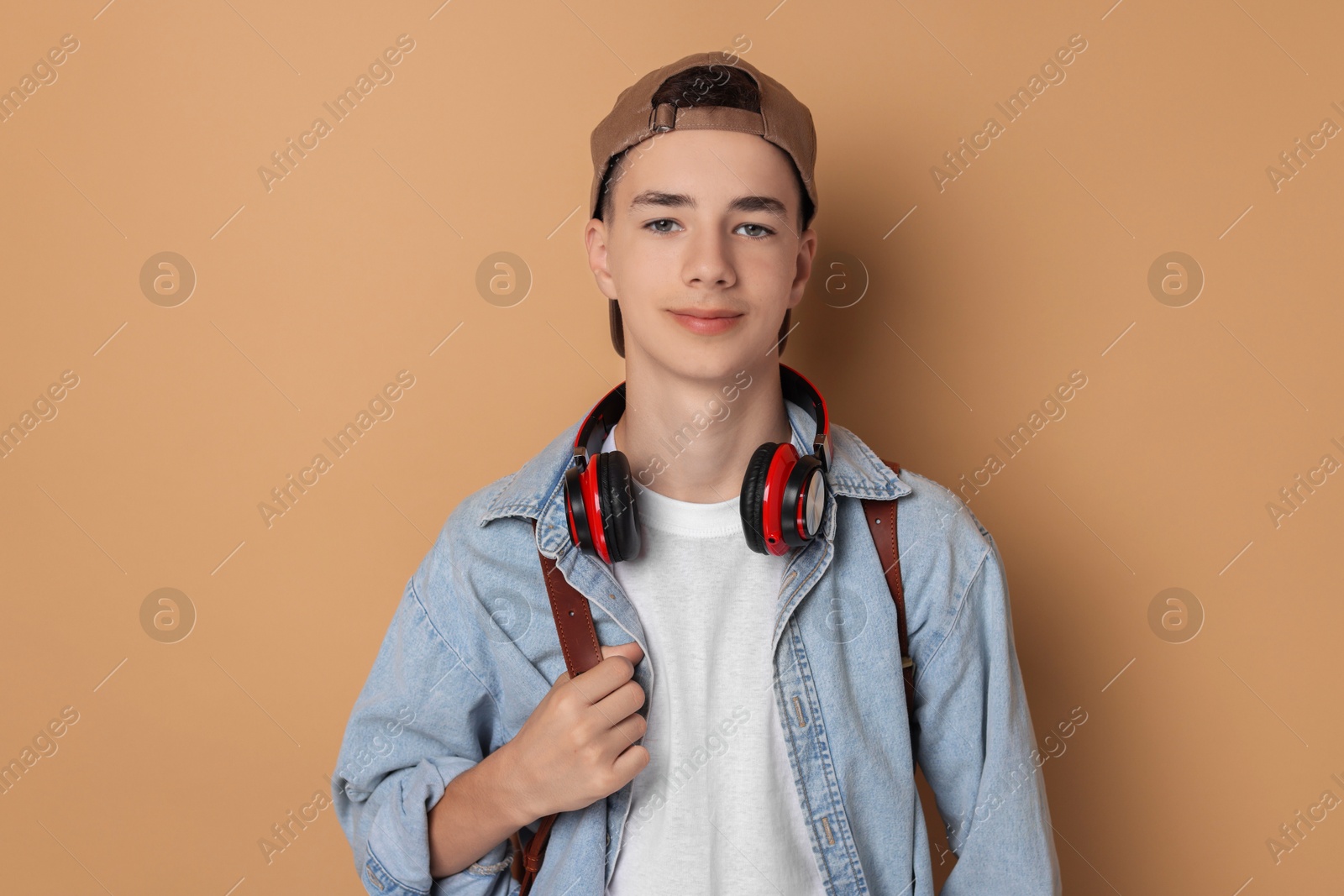 Photo of Portrait of teenage boy with backpack on dark beige background