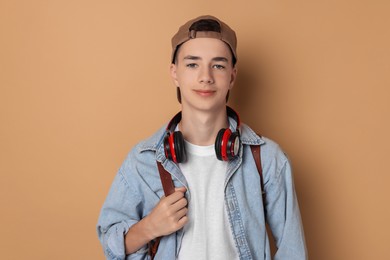 Portrait of teenage boy with backpack on dark beige background