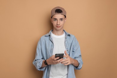 Photo of Portrait of teenage boy with smartphone on dark beige background