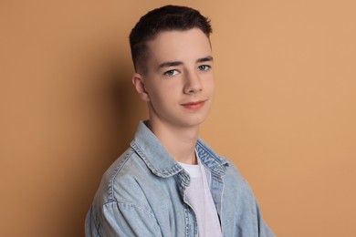 Portrait of teenage boy on dark beige background