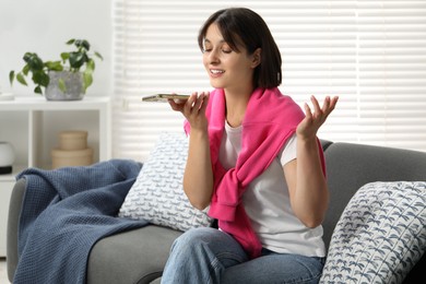 Photo of Beautiful woman recording voice message via smartphone at home