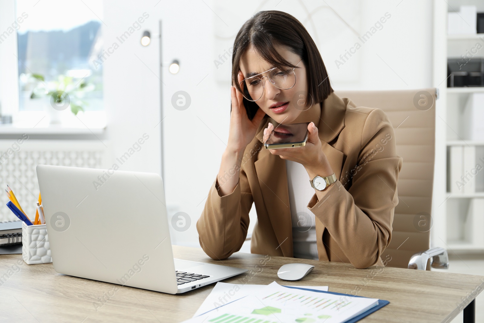 Photo of Beautiful woman recording voice message via smartphone in office