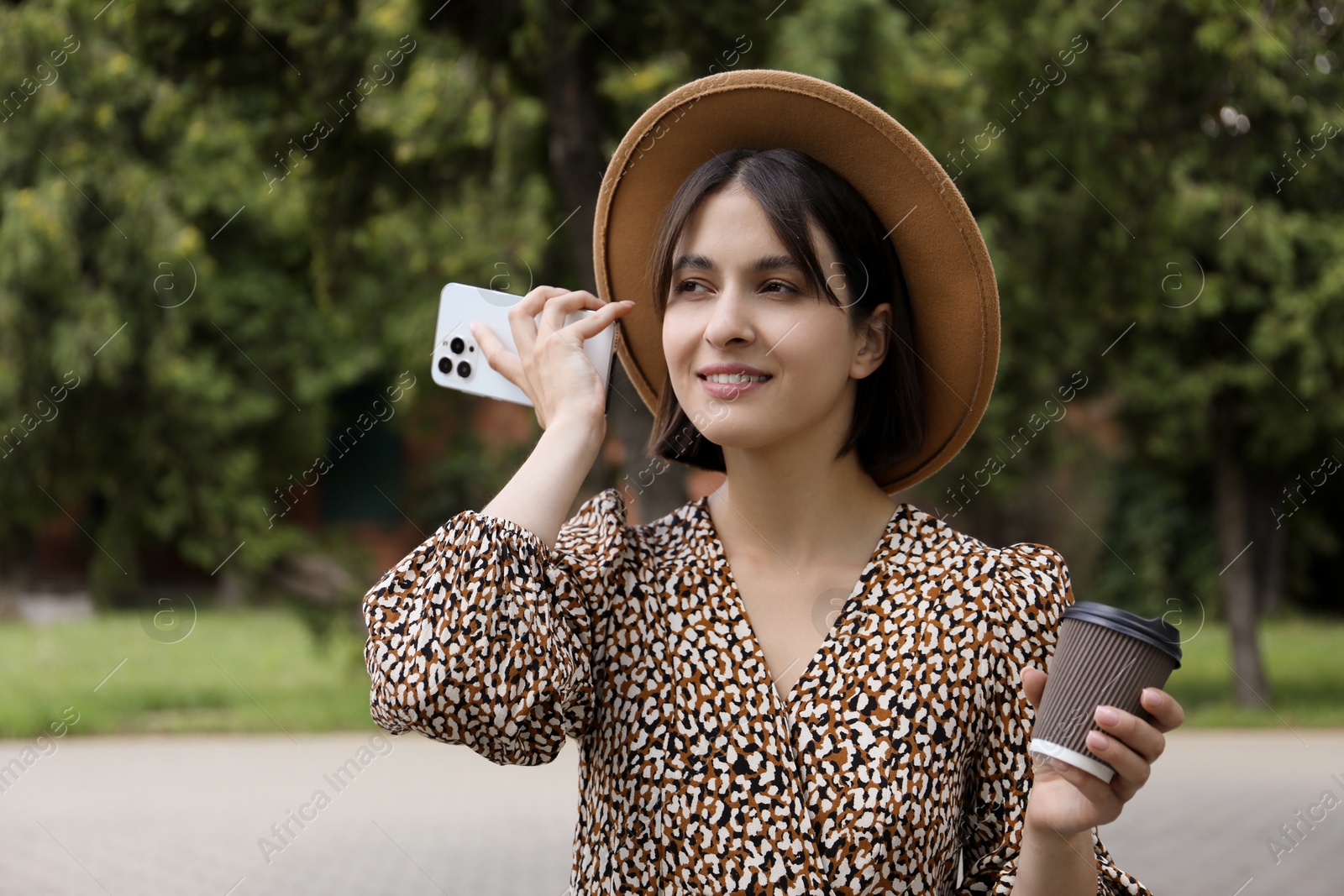 Photo of Beautiful woman with smartphone listening to voice message outdoors