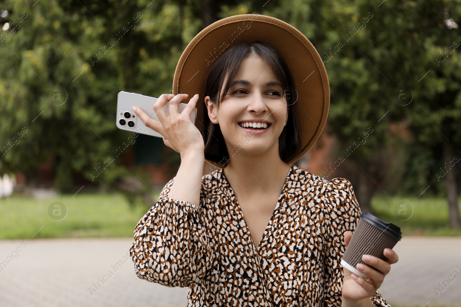 Photo of Beautiful woman with smartphone listening to voice message outdoors